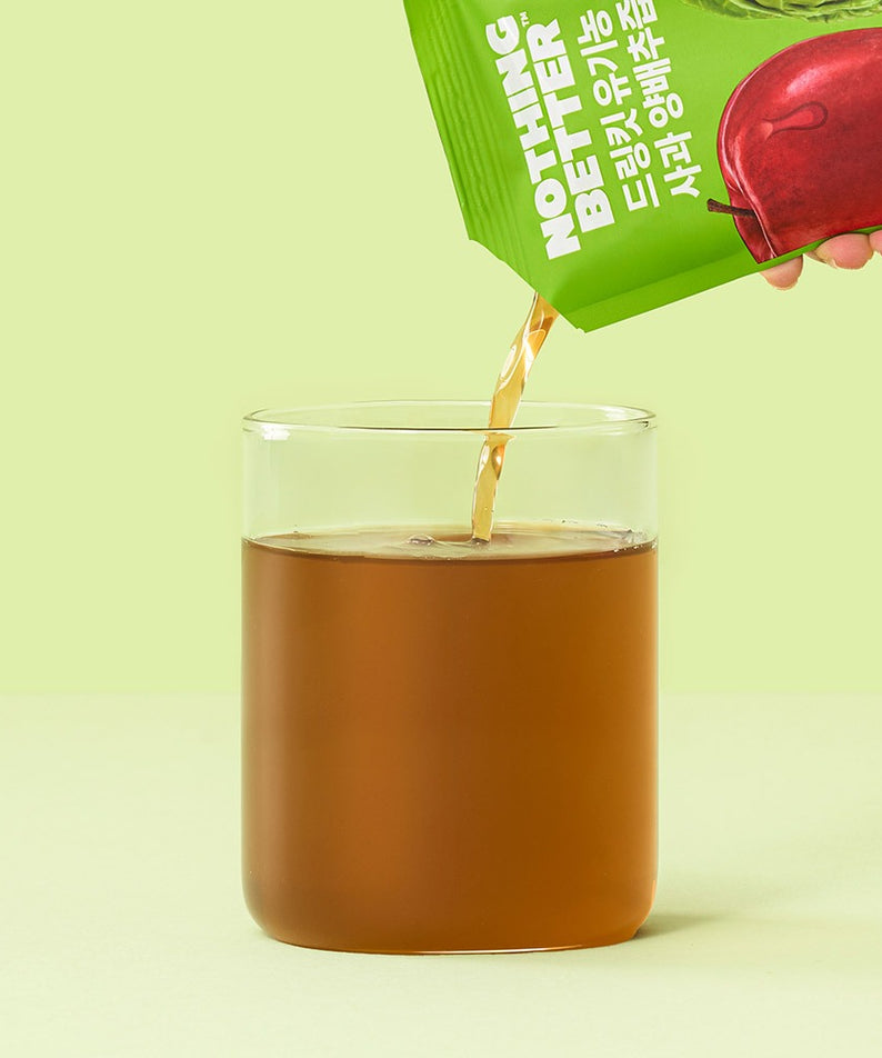Plan rapproché: NOTHING BETTER Drinkit Organic Applr Cabbage Juice 100ml 24 Packets, bouteille verte verse du jus dans verre, fond vert.