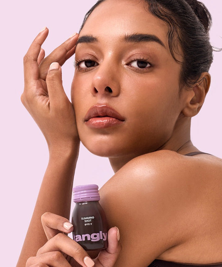 Femme tenant une bouteille de NOTHING BETTER Tangly Slimming Shot 7 Bottles, produit minceur moderne.