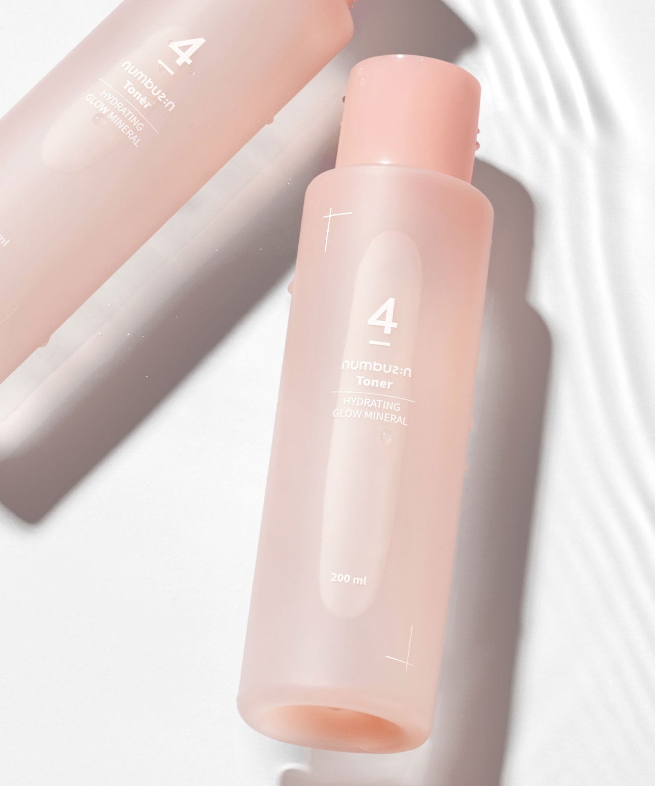 Bouteille de NUMBUZIN No.4 Hydration Glow Mineral Toner sur fond blanc texturé, soin de la peau hydratant et lumineux.
