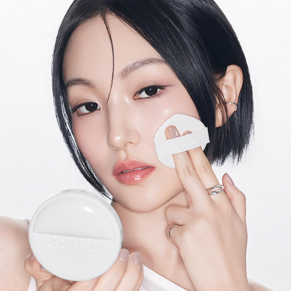 NUSE 1+1 Reju Toning Sun Cushion NUSE, visage maquillé appliquant une éponge, contexte beauté sur fond clair