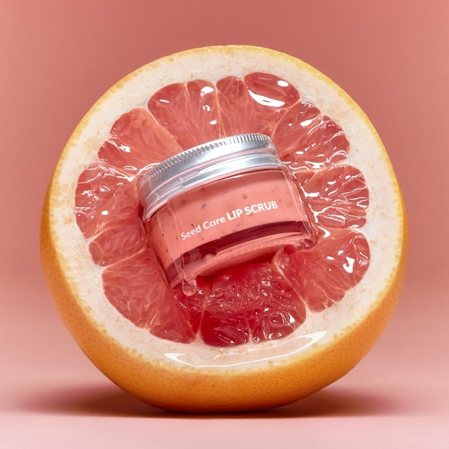 NUSE Seed Care Lip Scrub de NUSE, pot sur fond rose, rondelle de pamplemousse en arrière-plan