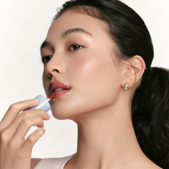 NUSE Care Lipstick sur lèvres d’une femme, maquillage soigné, marque NUSE, fond clair, produit en gros plan.