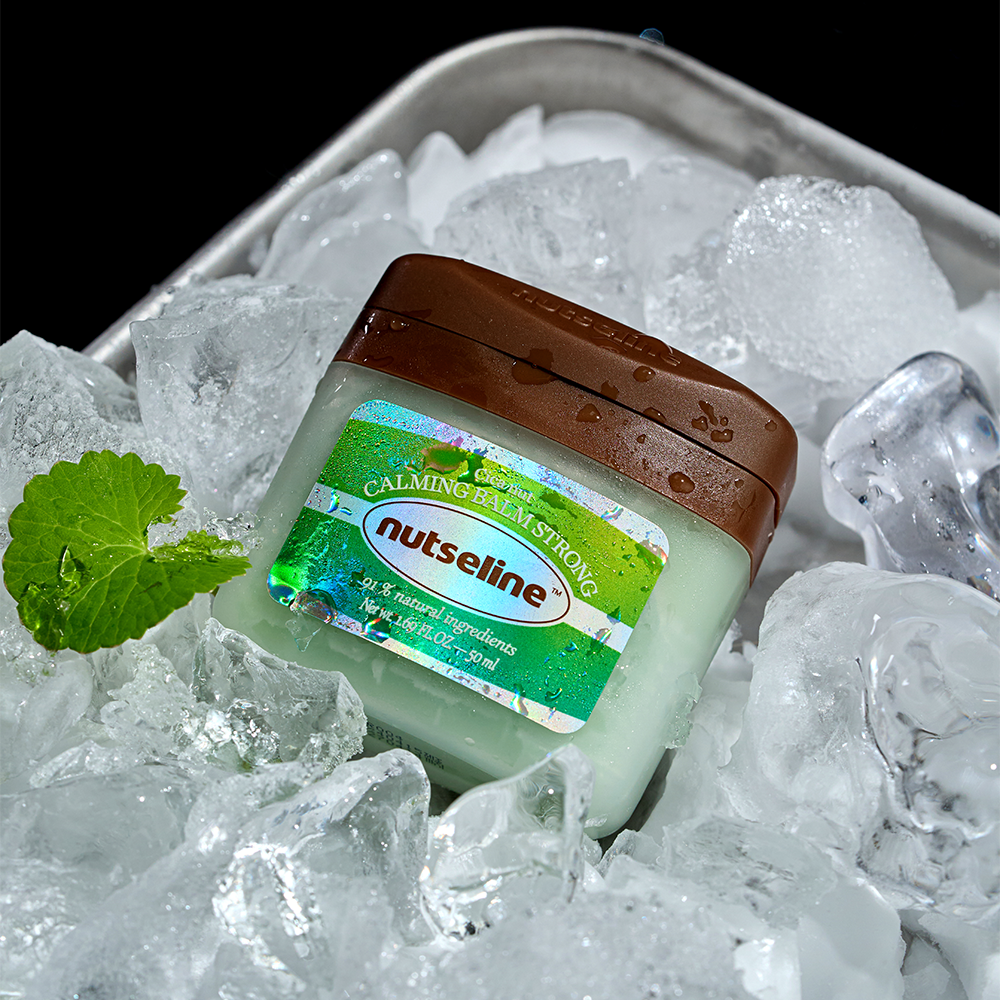 NUTSELINE Cica Nut Calming Balm Strong 50ml, baume apaisant NUTSELINE, sur glace avec menthe et contexte rafraîchissant.
