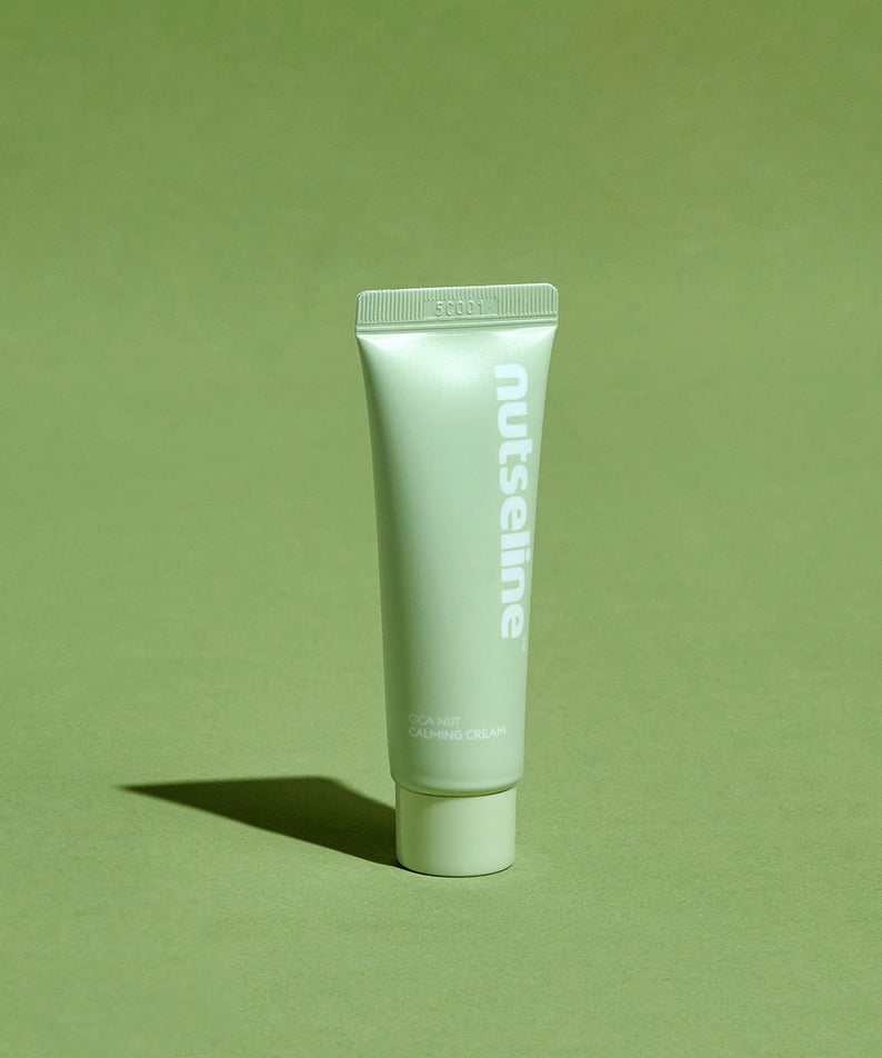 Décris l'image en français : NUTSELINE Cica Nut Calming Cream 25ml, tube vert de la marque NUTSELINE sur fond vert.