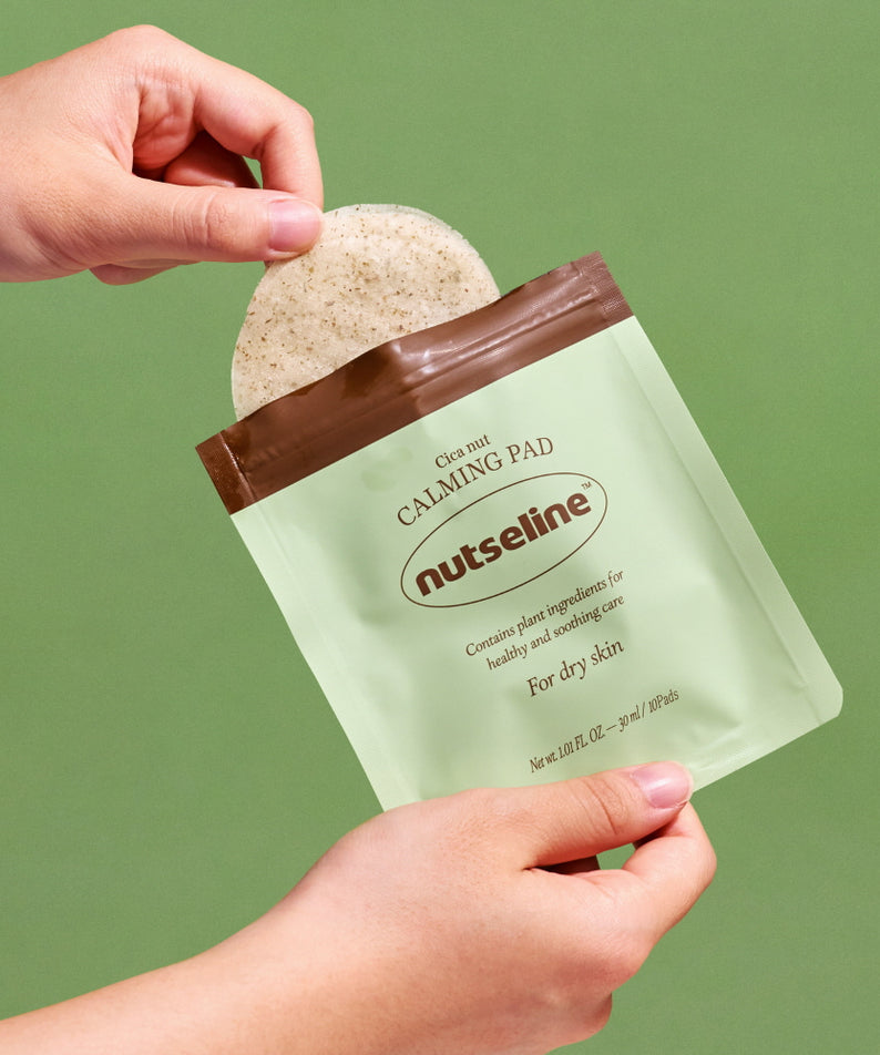 Une main tenant NUTSELINE Cica Nut Calming Pads sur fond vert.