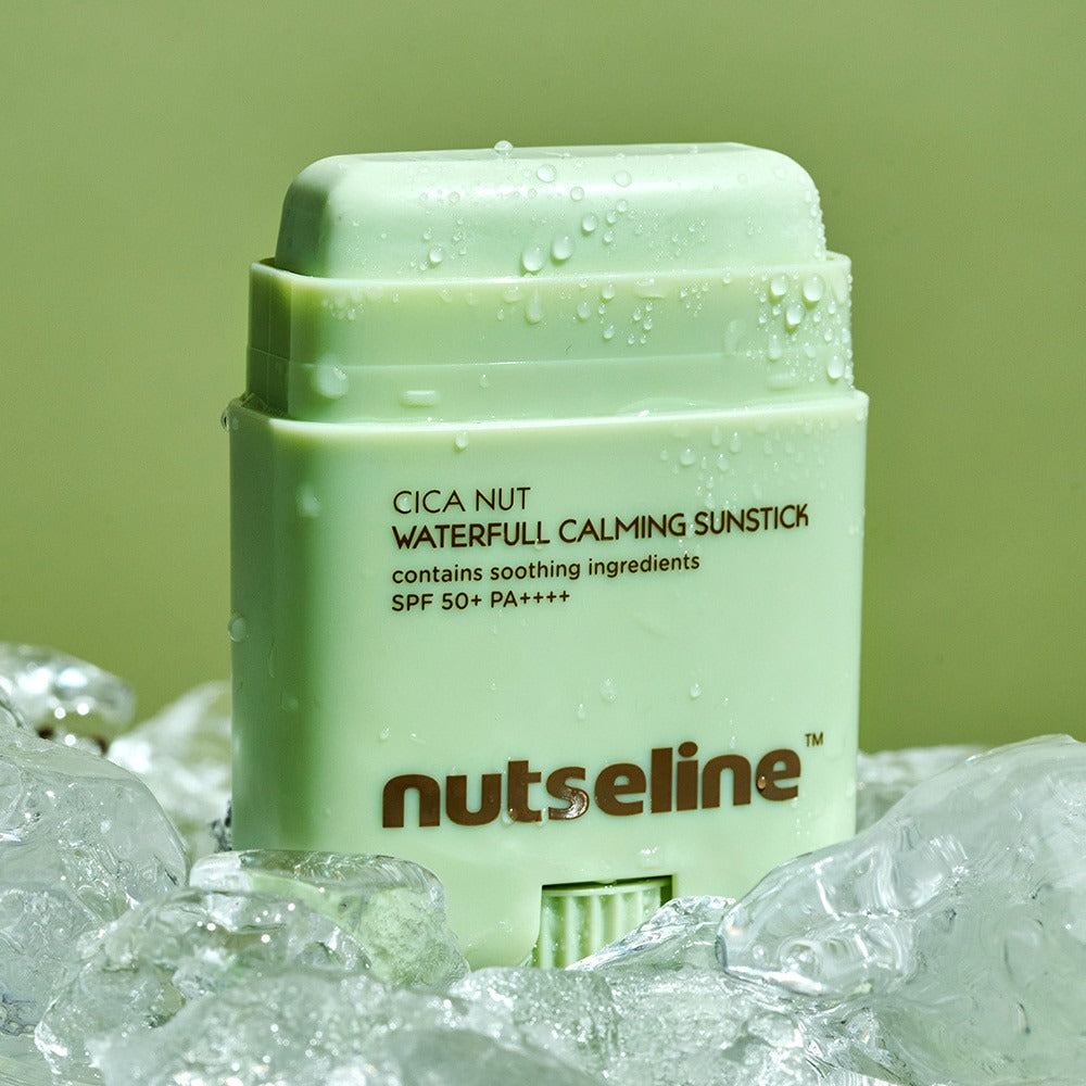 NUTSELINE Cica Nut Waterful Calming Sun Stick 20g, stick solaire apaisant de la marque NUTSELINE, sur fond vert avec gouttes d’eau.