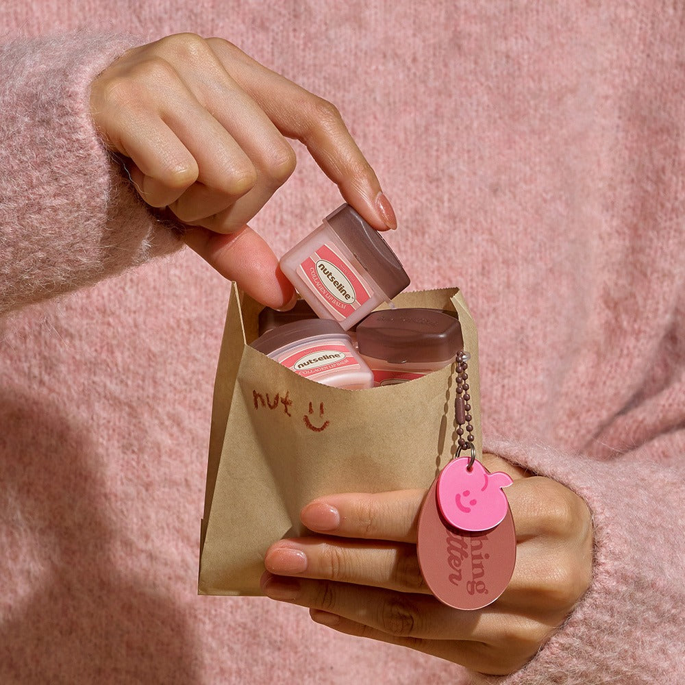 Décris l'image en français en mentionnant le produit, la marque et le contexte visuel : NUTSELINE Super Nut Collagen Keyring Lip Balm 11ml