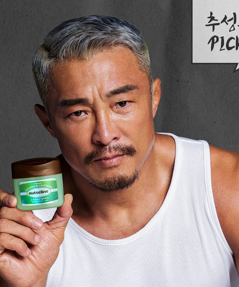 Homme tenant le NUTSELINE Cica Nut Calming Balm Strong 50ml, produit apaisant pour la peau, sélectionné pour ses bienfaits.