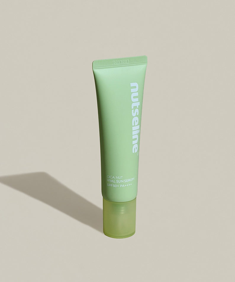 Image du sérum solaire NUTSELINE Cica Nut Hyal Sun Serum 50ml en tube vert sur fond beige.