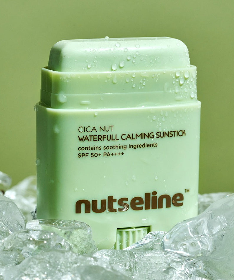 NUTSELINE Cica Nut Waterful Calming Sun Stick 20g en gros plan sur fond glacé, offrant une protection SPF 50+ et des ingrédients apaisants.