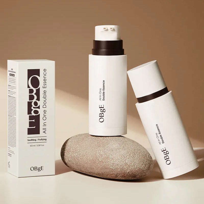 OBGE All-in-one double essence 100ml, flacon crème et boîte OBGE sur fond beige, style cosmétique minimaliste.