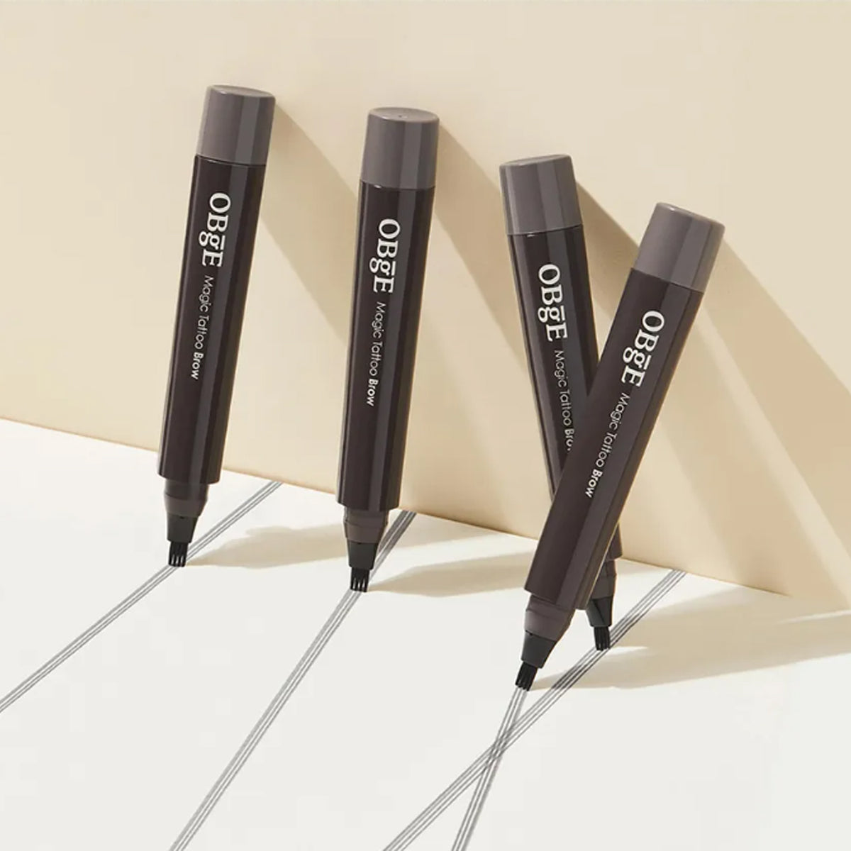 OBGE Magic Tattoo Brow de la marque OBGE, stylos pour sourcils, sur fond clair avec ombres et lignes fines.