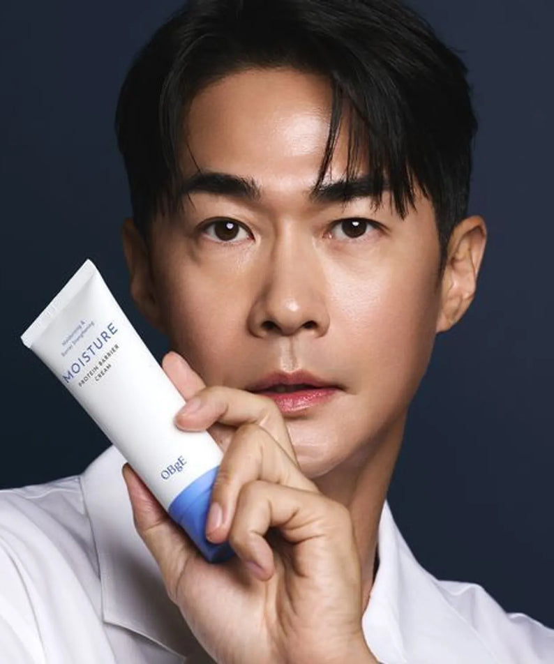 OBGE Moisture Protein Barrier Cream 150ml, tube blanc, présenté par un homme en studio sur fond bleu foncé.