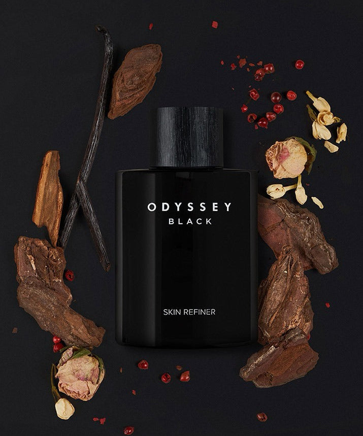 Flacon ODYSSEY Black Skin Refiner 130ml entouré d'ingrédients naturels raffinés sur fond sombre.