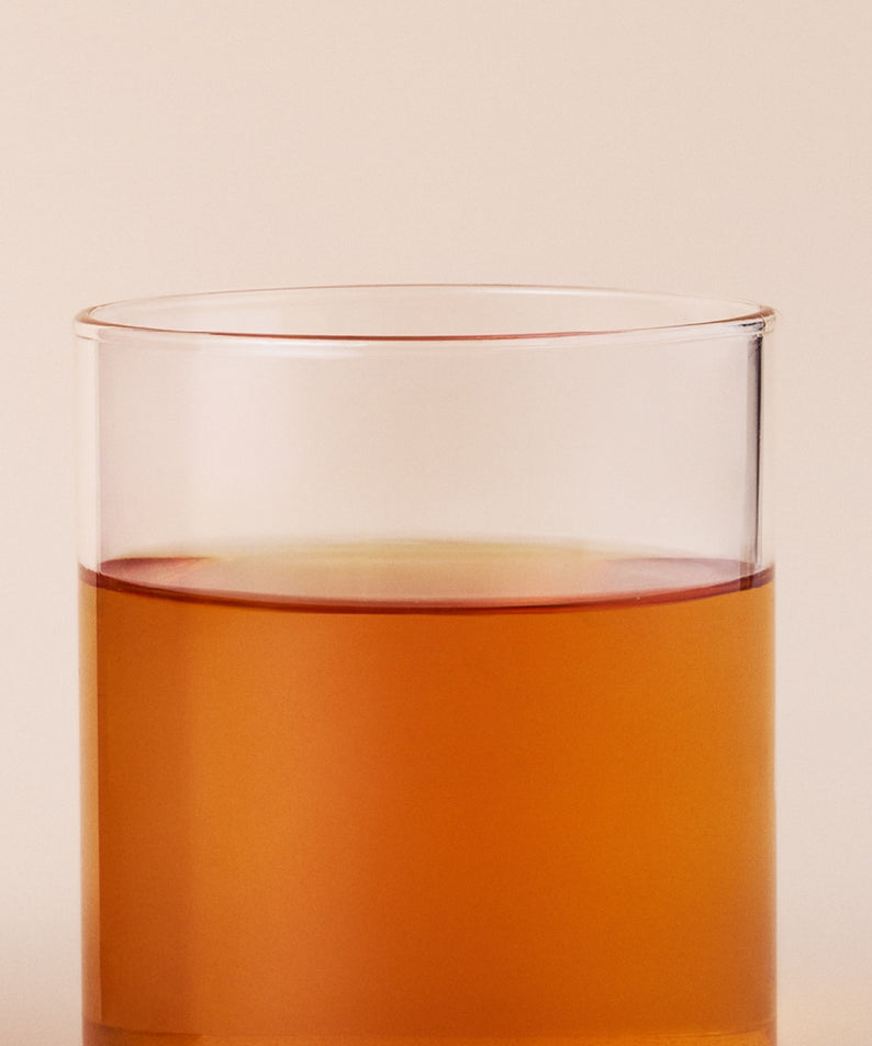 OSULLOC Fig Chocolate Black Tea 20 P : infusion ambrée en verre, arrière-plan beige, ambiance dégustation.