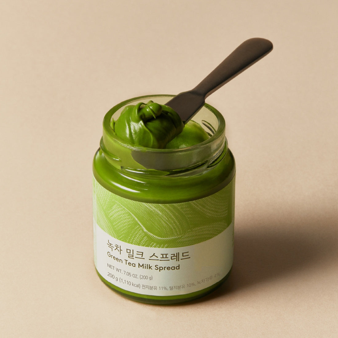 OSULLOC Green Tea Milk Spread 200g : pot vert en verre avec cuillère, style thé matcha, sur fond clair.