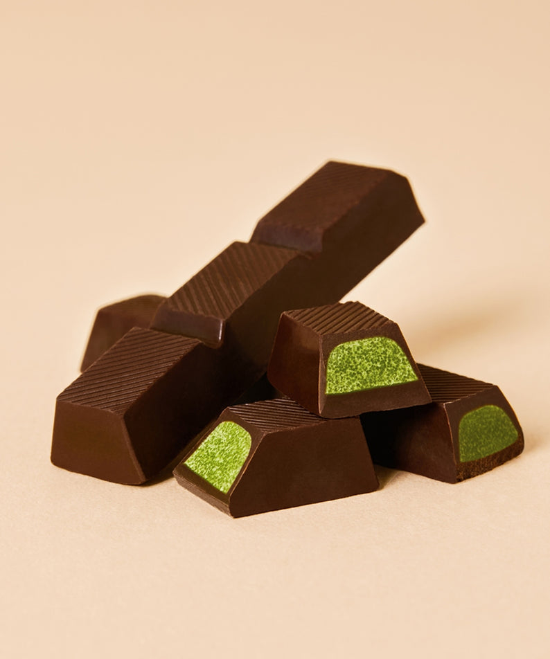 OSULLOC Jeju Island Green Tea Chocolate Bar 120g : morceaux de chocolat au thé vert, fond beige, ambiance produit.