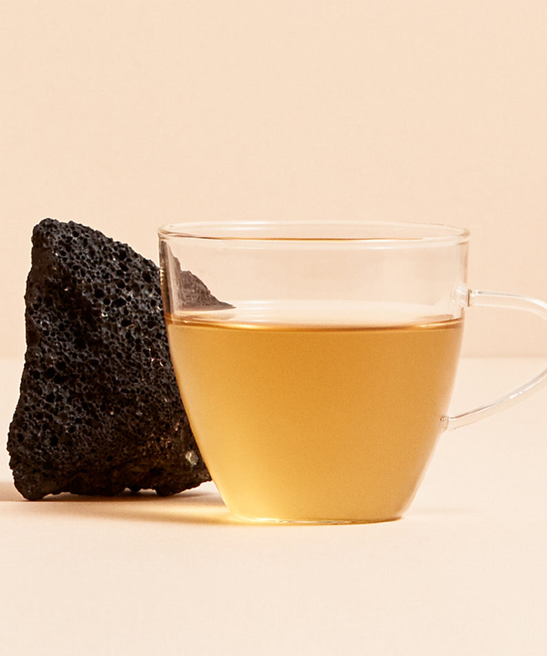 OSULLOC Jeju Volcanic Oolong Tea 20 P, tasse de thé oolong sur fond beige, roche volcanique en décor (marque OSULLOC).