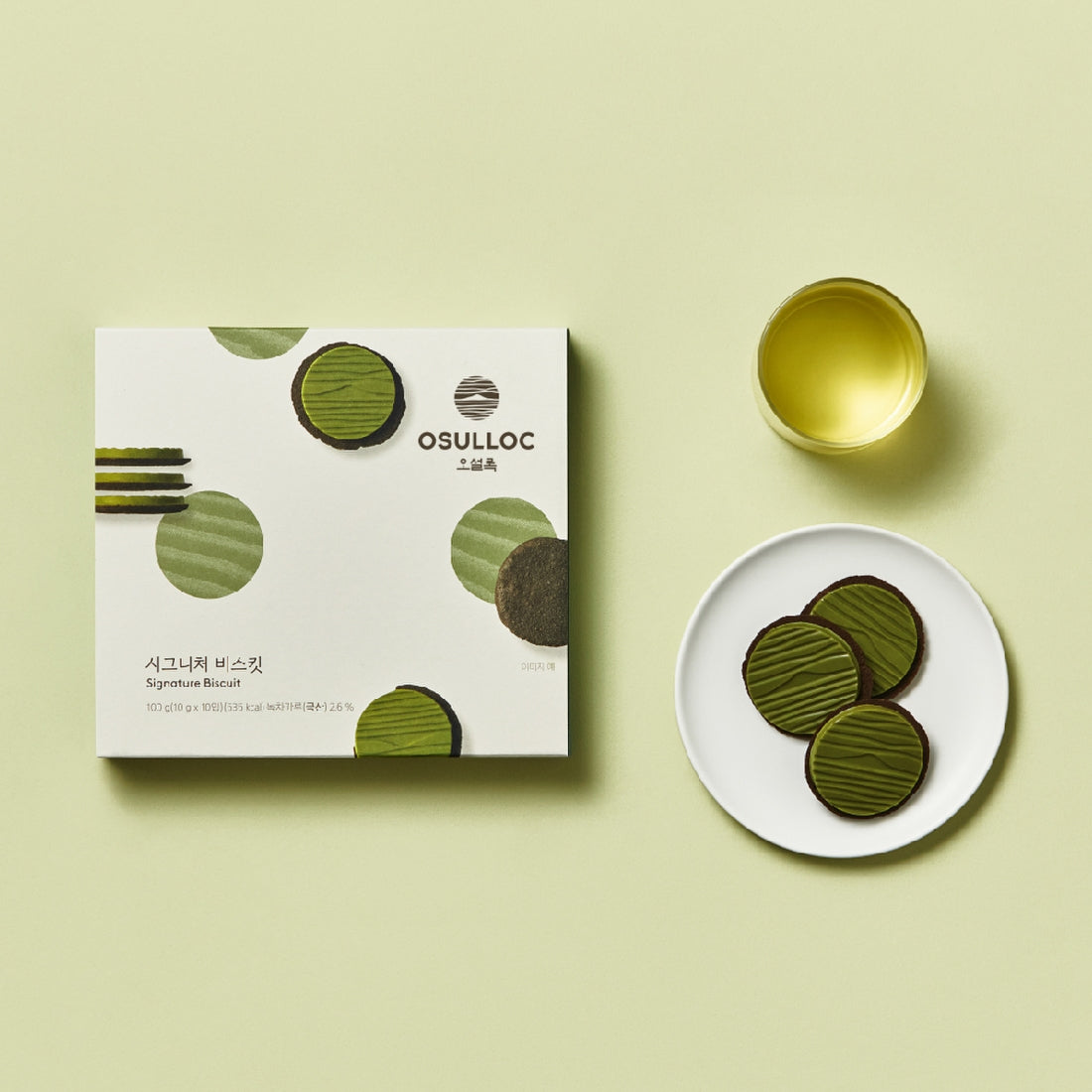 OSULLOC Signature Biscuits 10 P : boîte et biscuits sur fond vert clair, tasse dorée, vue produit.