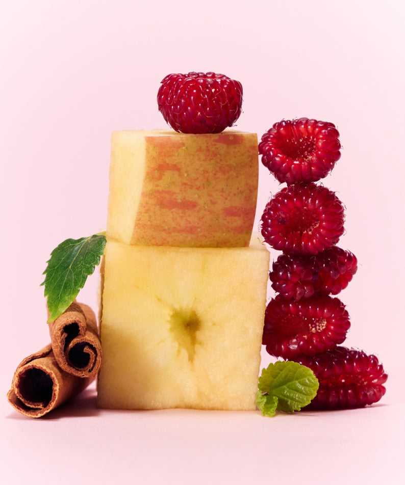 Cube de pomme et framboises fraîches sur fond rose, inspirant le mélange fruité du OSULLOC Berry Garden Green Tea 10 P.