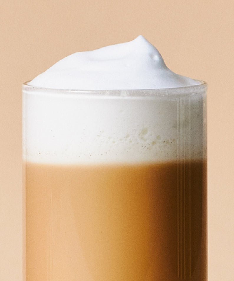 Verre de OSULLOC Earl Grey Milk Tea 10 p avec mousse crémeuse sur fond beige.