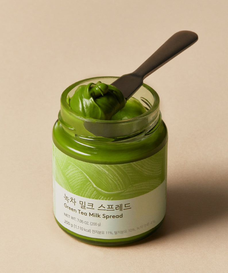 Pot de OSULLOC Green Tea Milk Spread 200g avec couteau sur le dessus, crème verte onctueuse.