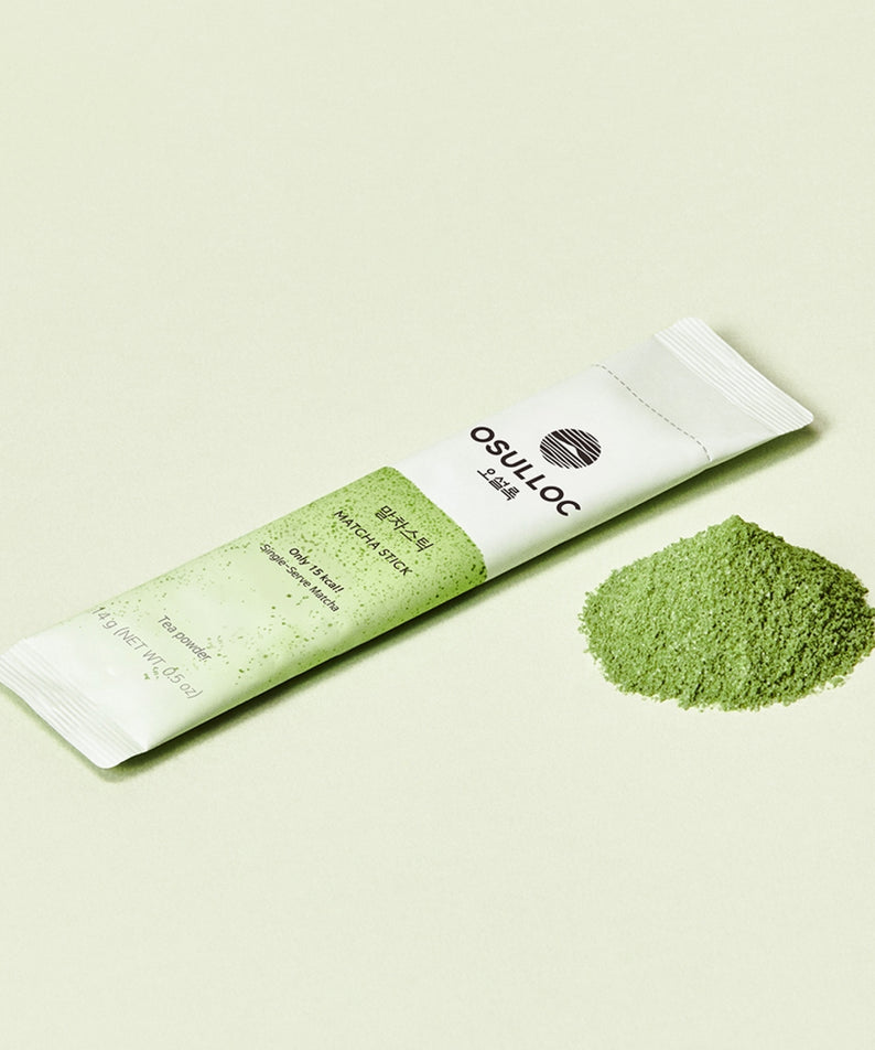 Stick de thé vert en poudre OSULLOC Matcha Sticks 5 p posé à côté d'une petite pile de poudre de matcha sur fond vert pâle.