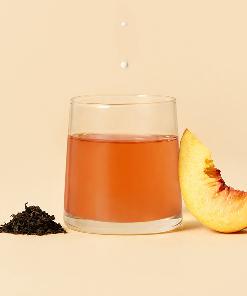 Verre de thé OSULLOC Milky Oolong Tea 10 p avec une tranche de pêche et thé en vrac en arrière-plan, beige élégant.