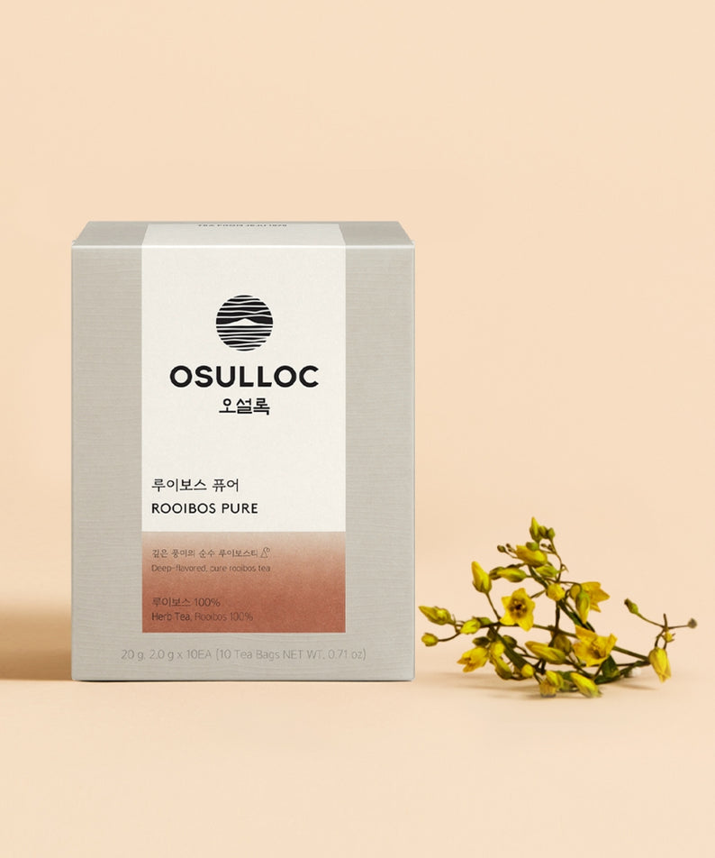 Boîte de thé OSULLOC Rooibos Pure 10 p. posée à côté de petites fleurs jaunes.