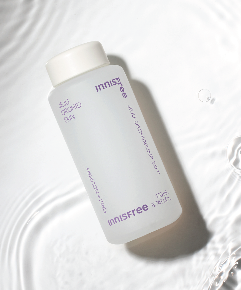 INNISFREE Jeju Orchid Skin 170ml de la marque Innisfree, flacon sur tissu blanc avec bulles d’eau, contexte visuel soin.
