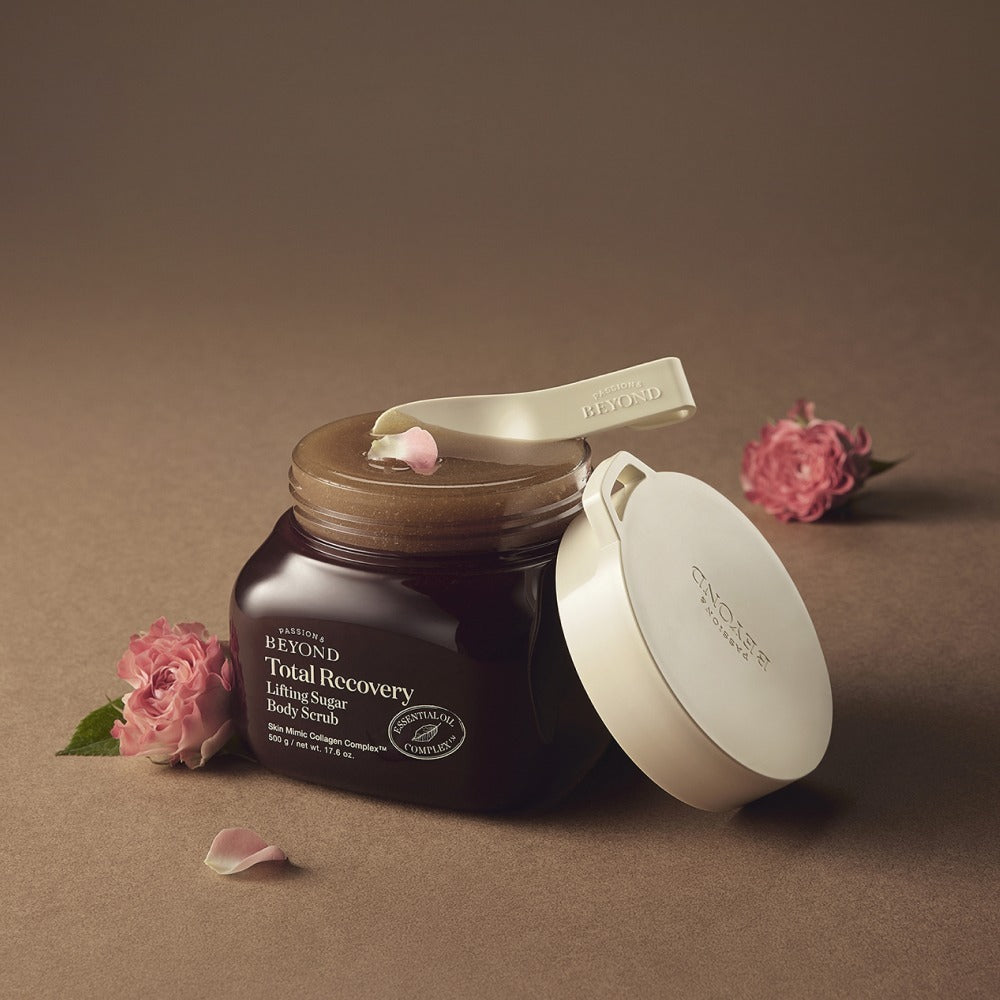 PASSION & BEYOND Total Recovery Lifting Body Scrub 500g, pot marron avec couvercle blanc, fleurs et pétales sur fond beige.