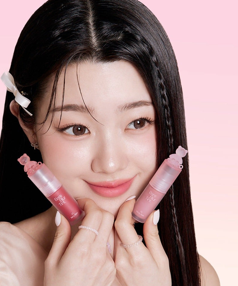 Femme souriante tenant deux tubes de PASSION CAT Bere Blur Tint devant fond rose.