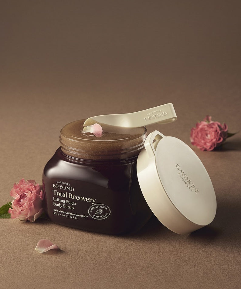 PASSION&BEYOND Total Recovery Lifting Body Scrub 500g avec fleurs roses, pot ouvert sur fond beige, soin du corps luxueux.