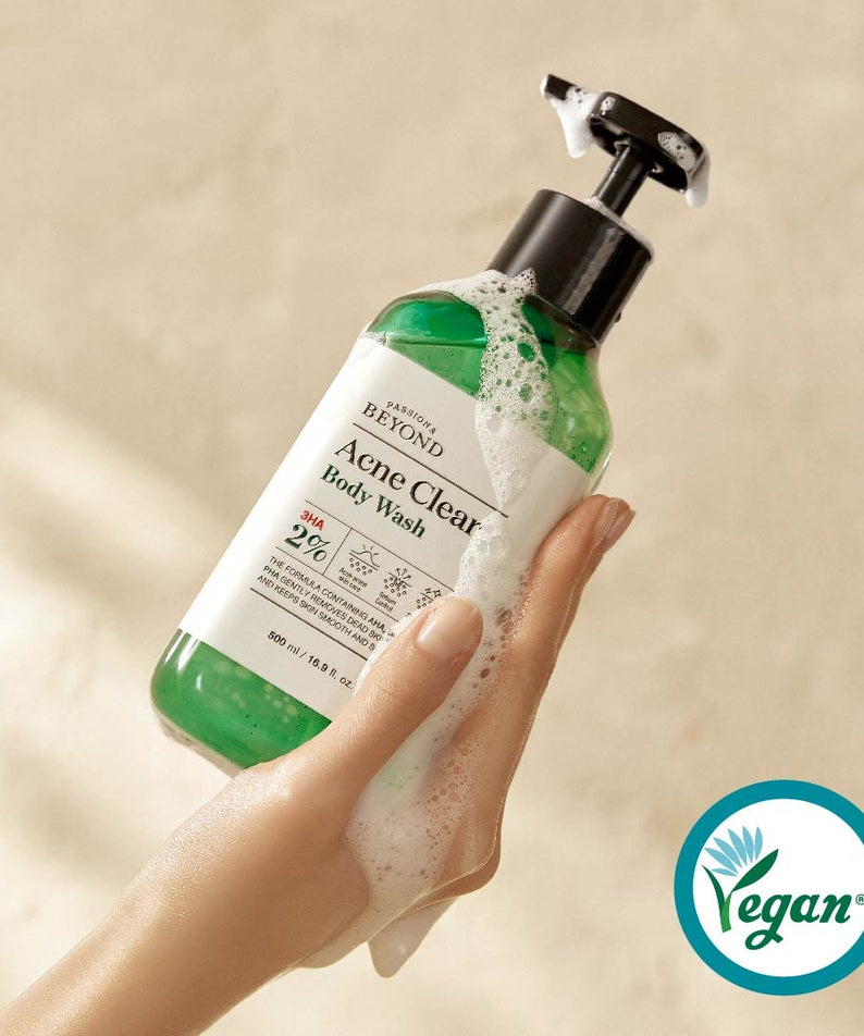PASSON & BEYOND Acne Clear Body Wash 500ml : main tient le gel nettoyant anti-acné, mousse sur fond beige. Marque visible.