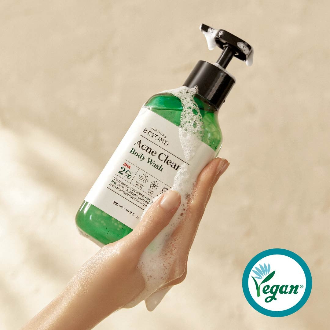 PASSON & BEYOND Acne Clear Body Wash 500ml : main tient le gel nettoyant anti-acné, mousse sur fond beige. Marque visible.