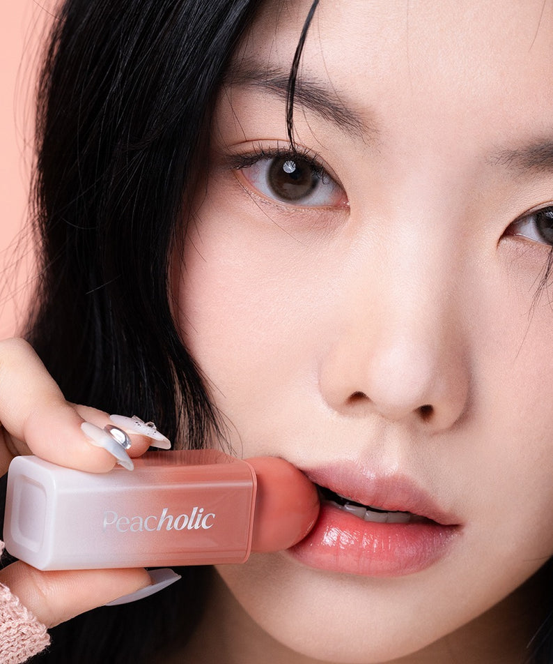 PEACHOLIC Water Glow Lip Tint par Peacheolic, gros plan lèvres hydratées tenant le tube, fond rose pastel