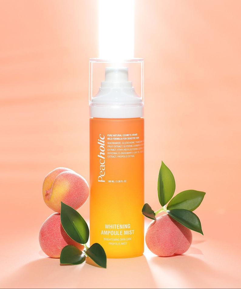 PEACHOLIC  Whitening Ampoule Mist 100ml, bouteille blanche sur fond pêche avec feuilles et fruits, mise en scène maquillage.