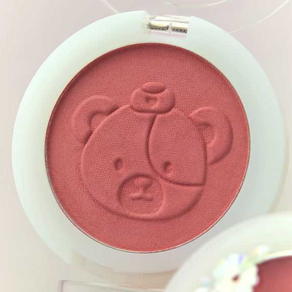 Décris l'image en français : PERIPERA Pure Blushed Sunshine Cheek, blush rose sur étui blanc, gros plan en lumière douce.