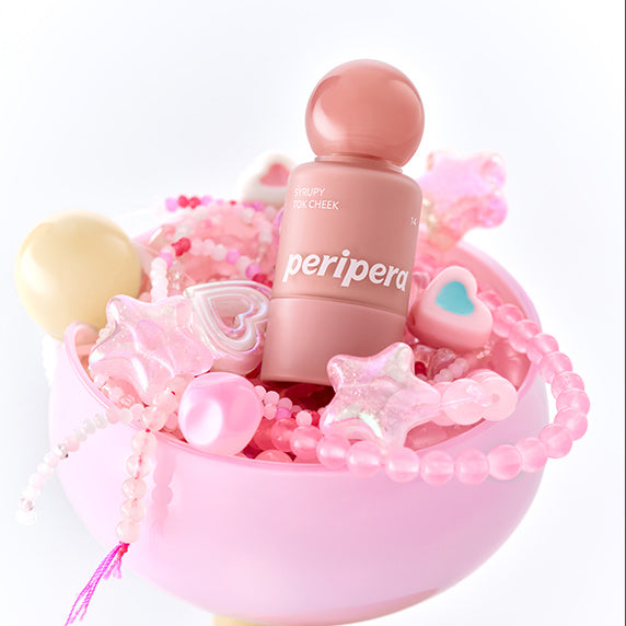 PERIPERA Syruppy Tok Cheek, pot de blush rose sur décor pastel rose, bonbons et billes, mise en scène cosmétique.