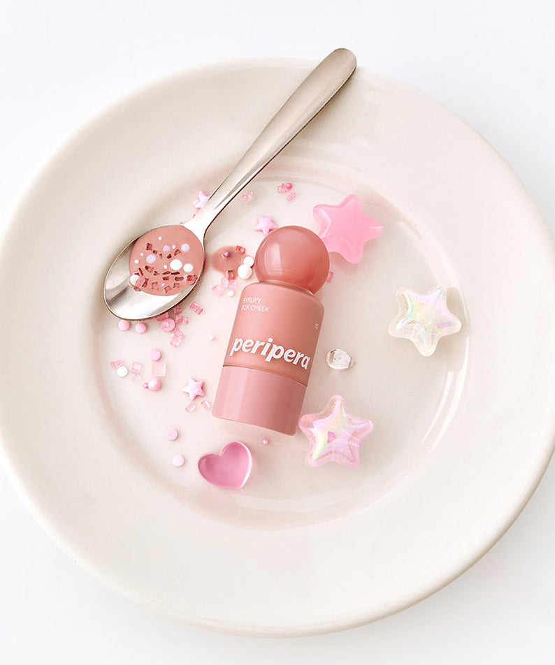 PERIPERA Syruppy Tok Cheek de la marque Peripera, packaging rose sur assiette blanche décorée d’étoiles et cœurs.
