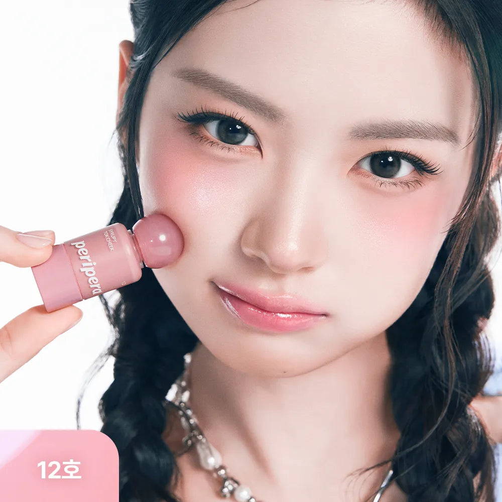 Décris l'image : PERIPERA Syruppy Tok Cheek, la marque, maquillage rosé sur la joue, femme aux yeux et peau lumineuse.