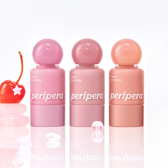 Décris l'image en français : PERIPERA Syruppy Tok Cheek, tubes et bouchons roses sur fond clair, beauté et reflet miroir.