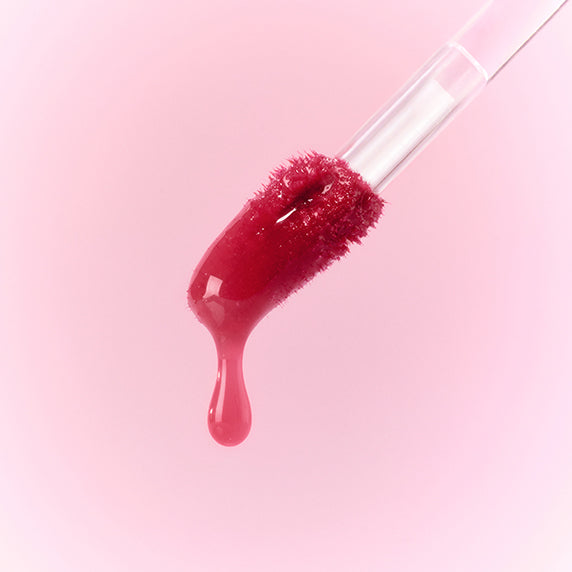 PERIPERA Water Bare Tint, rouge à lèvres liquide en goutte sur fond rose, bouteille transparente de la marque