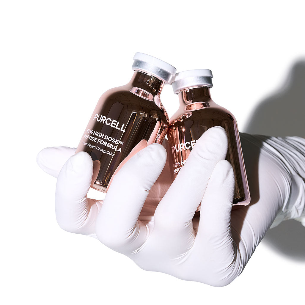 PURCELL 82% High Dose™ Peptide Formula 30mL, flacons tenus par des gants médicaux en contexte de soin.