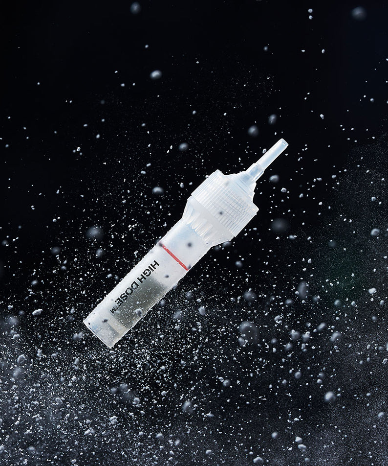 Décris l'image en français : PURCELL PixelBiome™ Booster Shot Powder 5ea de la marque PURCELL, poudre projetée sur fond noir.