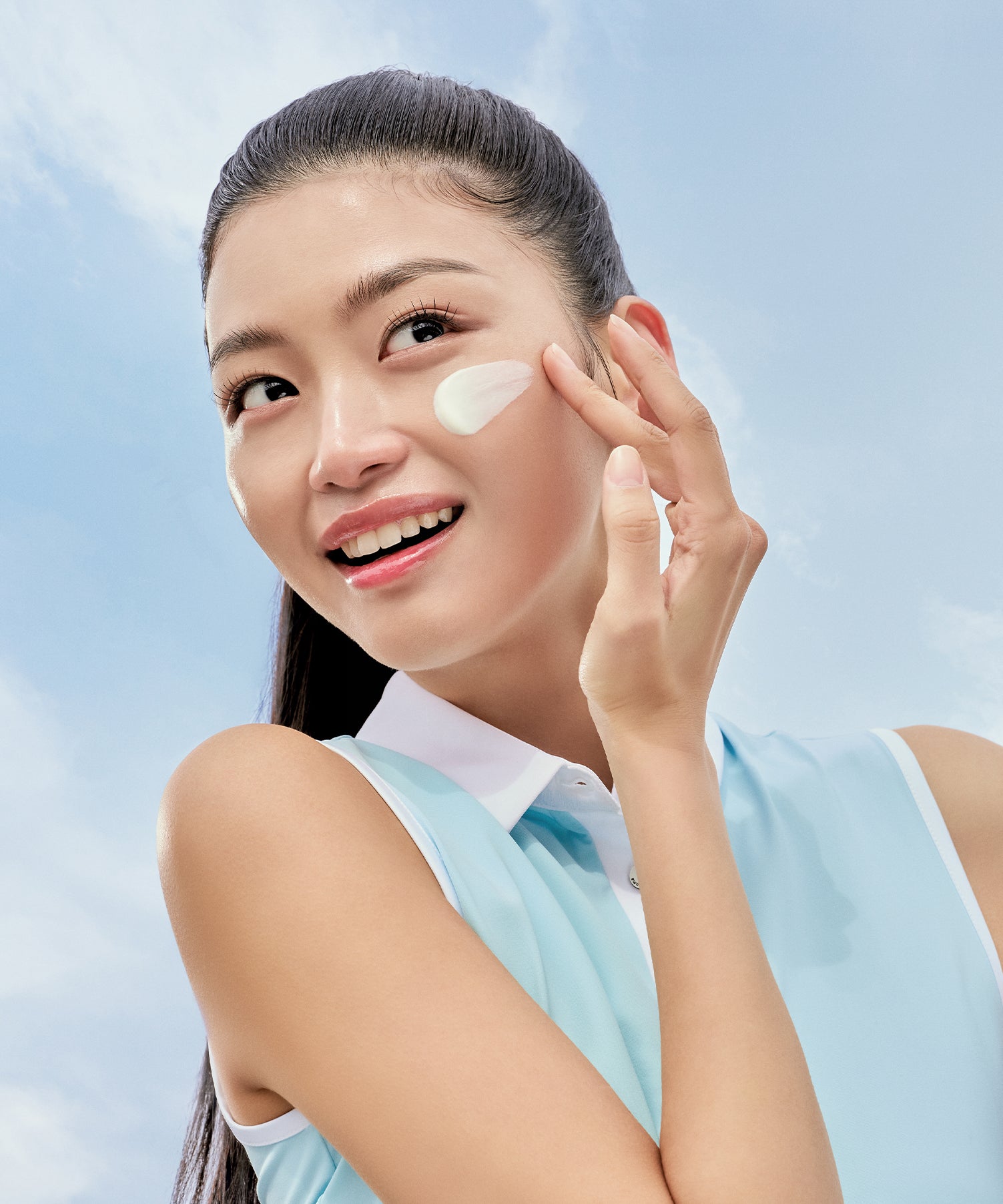 PURITO Daily Soft Touch Sun Cream SPF50+PA++++ sur le visage, femme appliquant une crème solaire par ciel bleu