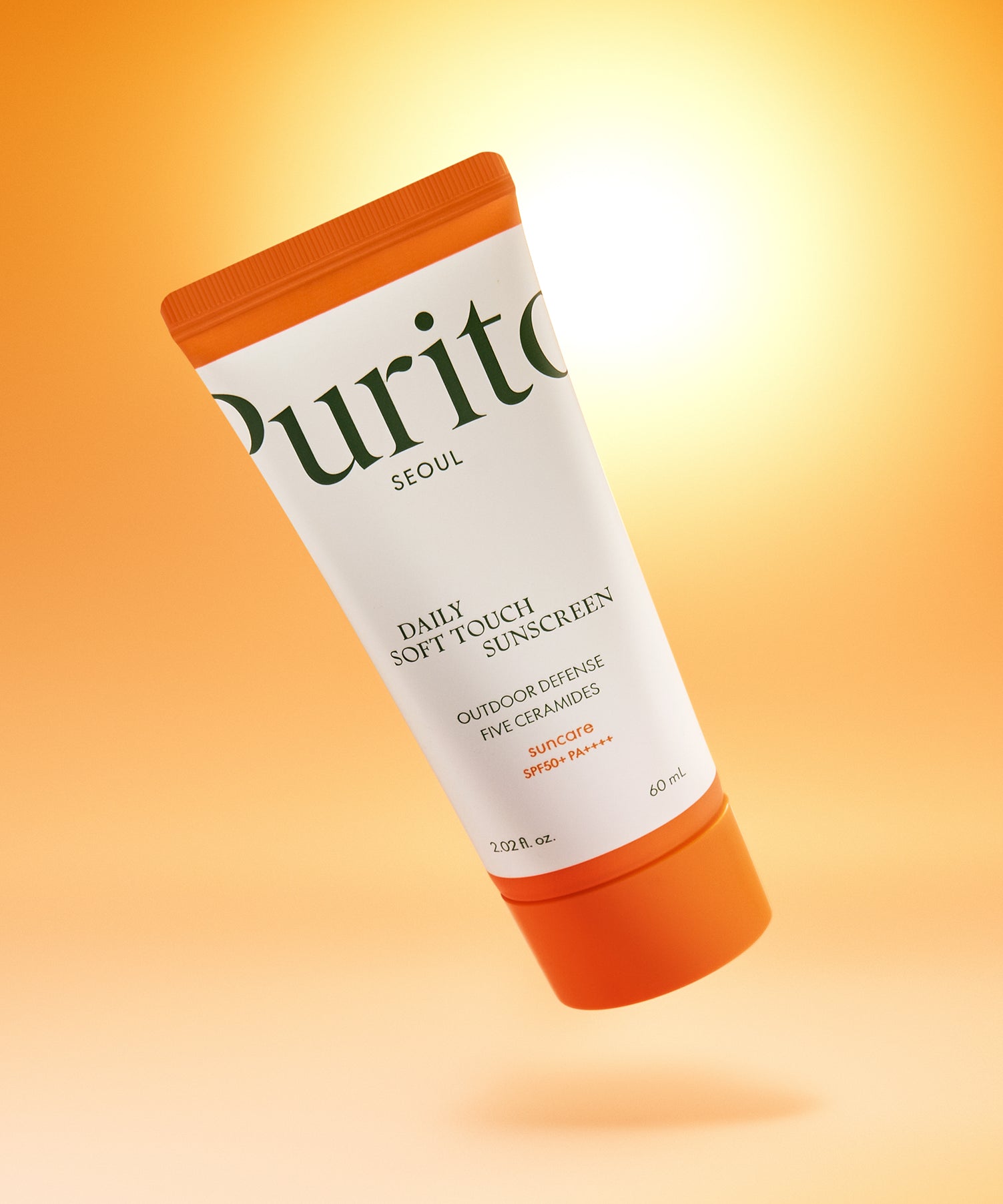 PURITO Daily Soft Touch Sun Cream SPF50+PA++++ de Purito, tube solaire orange sur fond jaune, éclairage doux, studio.