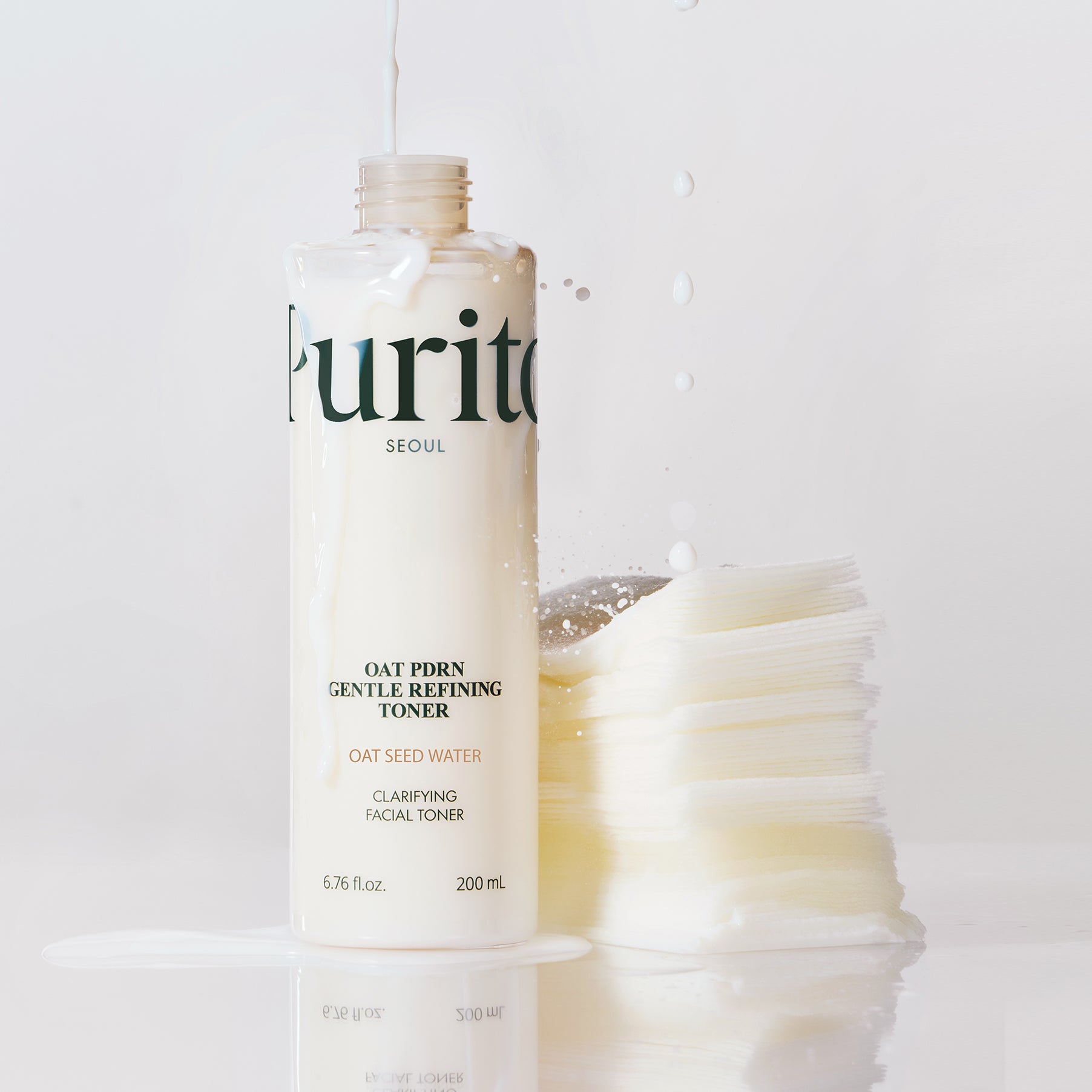 PURITO Oat PDRN Gentle Refining Toner 200ml, flacon crème sur fond blanc avec éclaboussures, branding Purito.