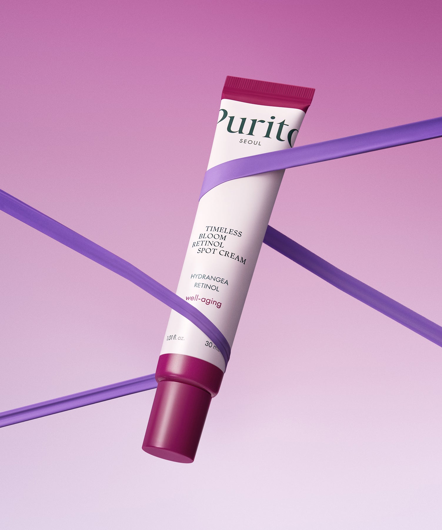 PURITO Timeless Bloom Retinol Spot Cream 30ml de Purito, tube cosmétique sur fond violet, posé sur des diagonales.