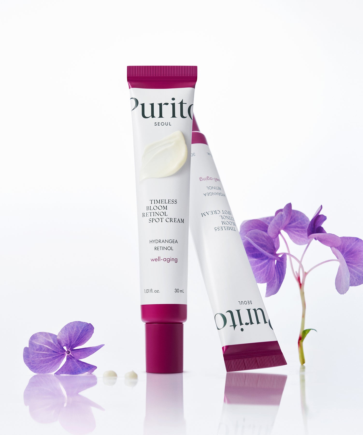 Décris l'image en français : PURITO Timeless Bloom Retinol Spot Cream 30ml, crème anti-taches PURITO sur fond blanc, fleurs violettes.